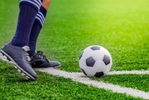 Soccer player with ball on grass field.